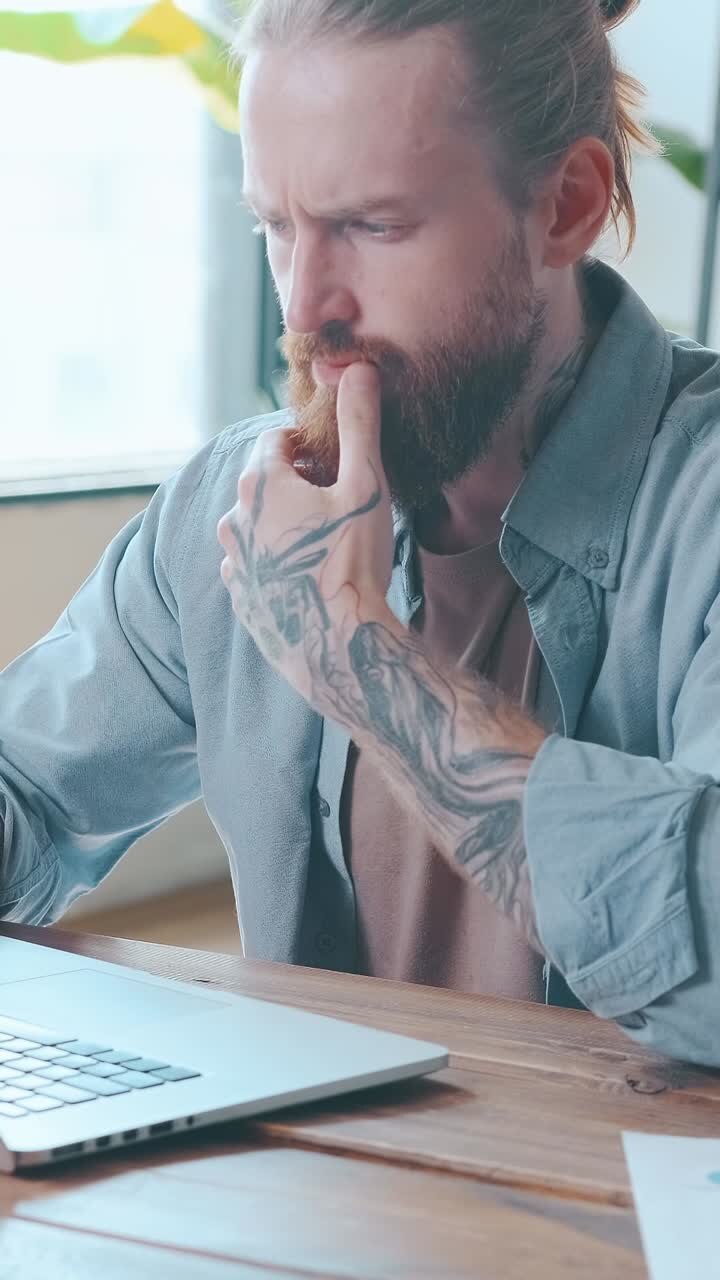 Uomo concentrato lavora intensamente al portatile in un caffè accogliente.