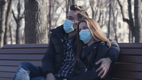 couple sitting on a park bench during covid-19 pandemic