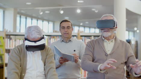 senior men using virtual reality glasses with teacher in library