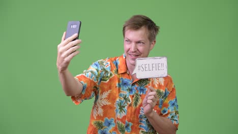 young handsome tourist man taking selfie with paper sign