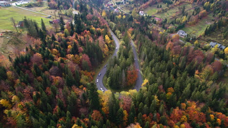 Winding-mountain-road-trough-the-forest-in-the-autumn-with-cars-passing-on-the-road