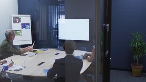 Diverse-business-colleagues-sitting-looking-at-screen-in-office-meeting