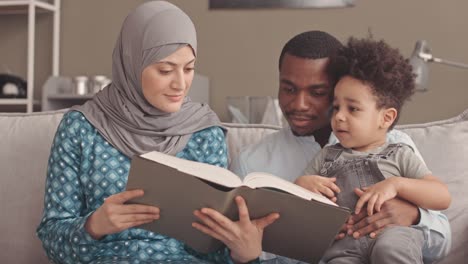 interracial muslim couple reading quran to little son
