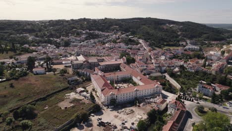 Historic-landmark-of-Portugal,-Alcobaça-monastery-and-surrounded-landscape,-aerial-pan-shot