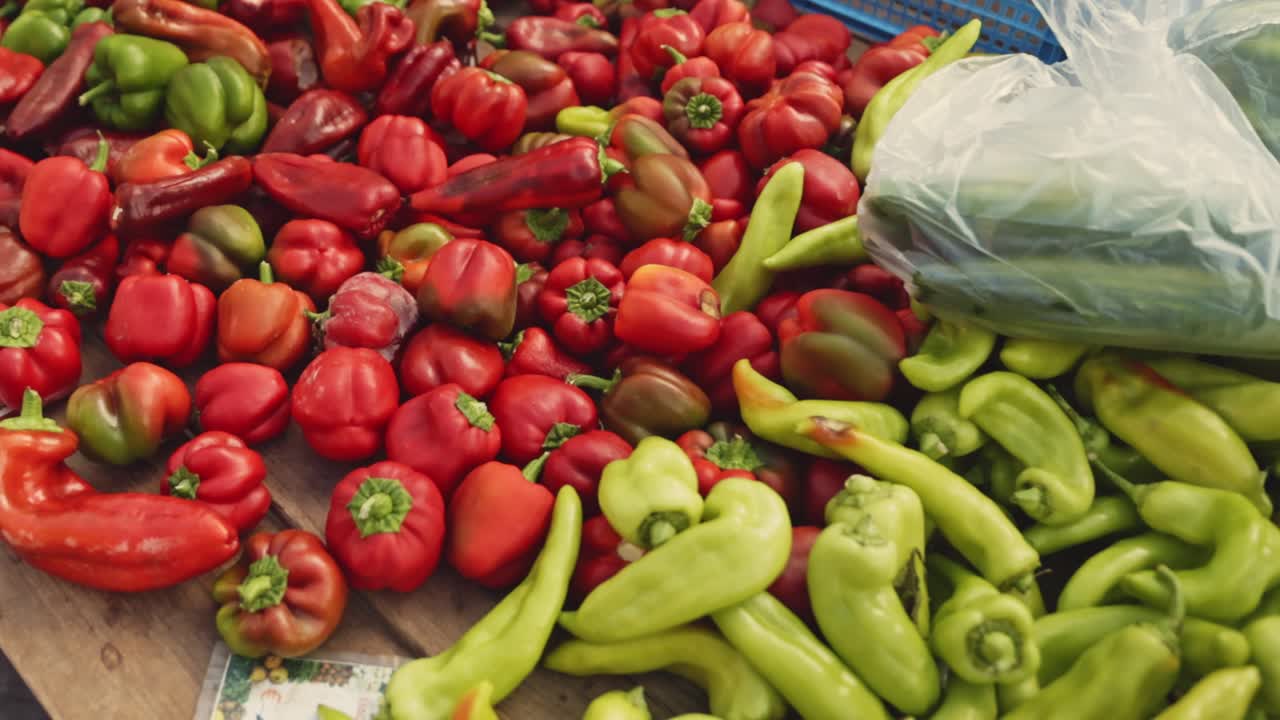 A close-up of ripe, colorful peppers and tomatoes displayed at a Greek farmers' market, showcasing fresh Mediterranean produce.