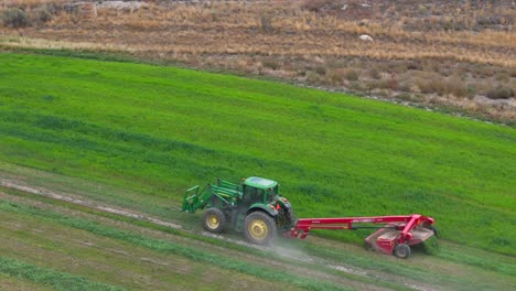 aerial hay harvesting: green tractor in action on a circular field in british columbia