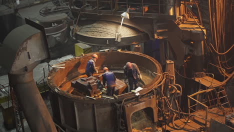 trabajadores de la fábrica de acero cargando materiales en el horno