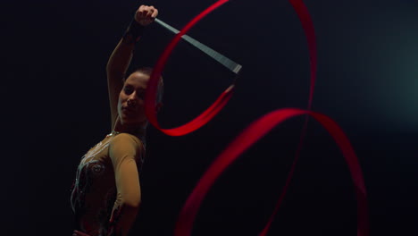 rhythmic gymnast exercising with ribbon indoors. girl posing with flying tape.