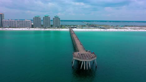 drone view flying past and to the right side of the navarre beach pier in northwest florida