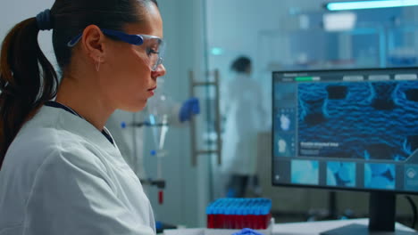 Lab-techinican-woman-sighing-at-camera-while-working-at-pc