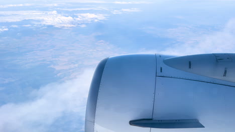 Engine-view-from-airplane-window,-cloudscape-and-blue-skies,-high-altitude