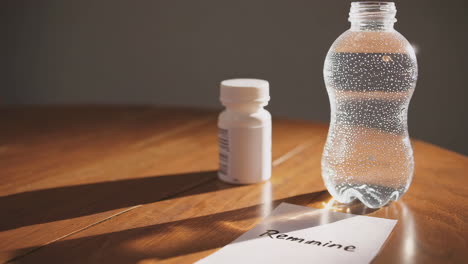 water bottle, pills, and note on a wooden table