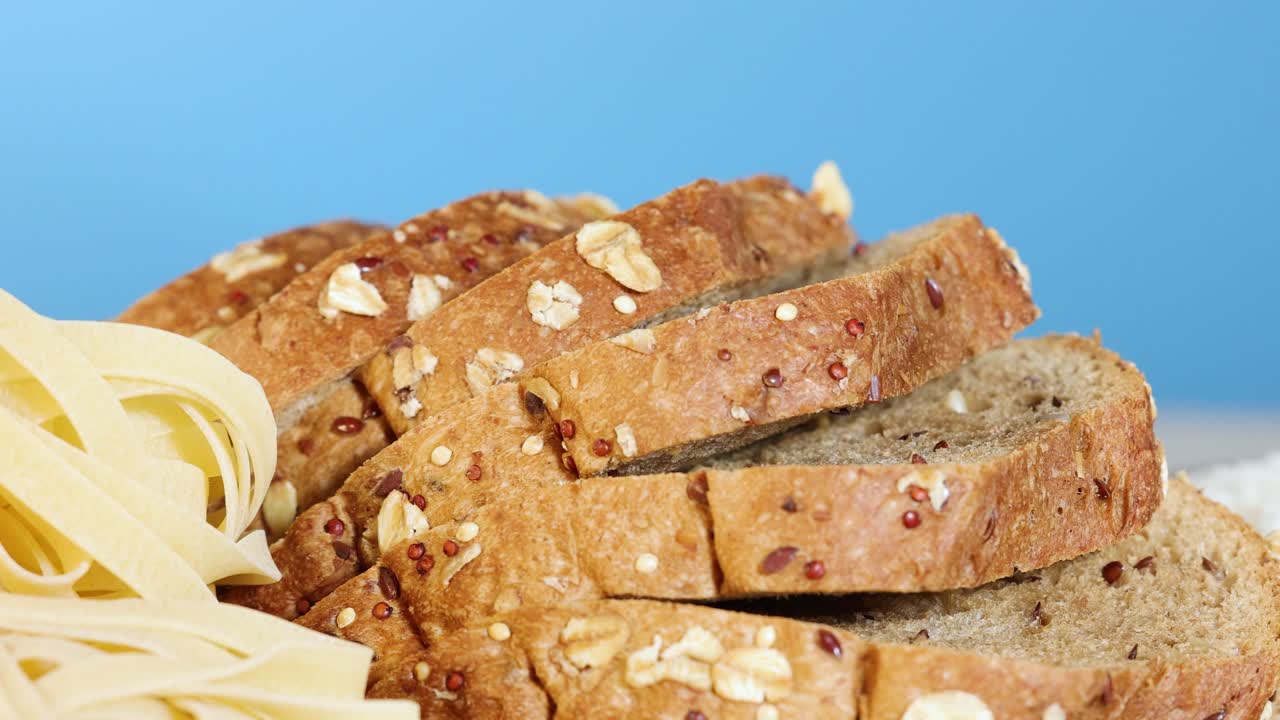 A hand selects a slice from a stack of whole wheat bread against a blue background, highlighting texture and freshness