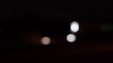 faros de coche fuera de foco, bolas de bokeh en movimiento, noche
