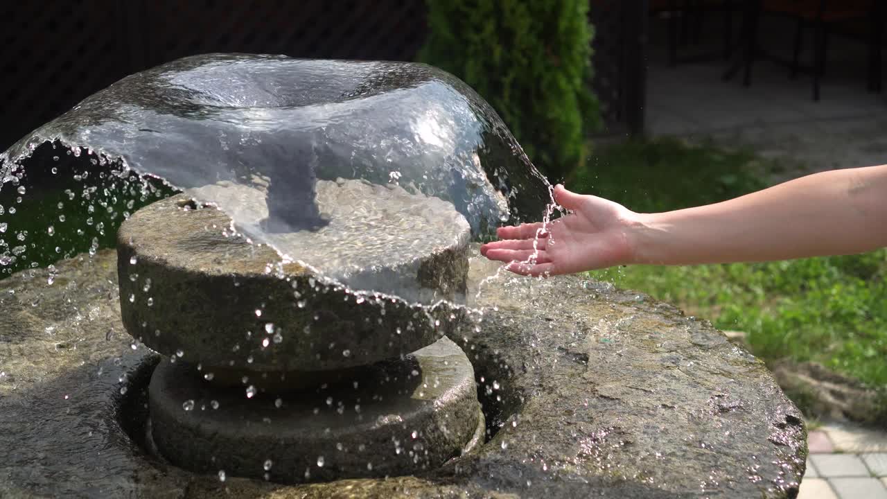 la mano de una mujer en el chorro de agua en la fuente 01