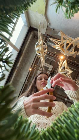 woman decorating a christmas tree with wooden ornaments