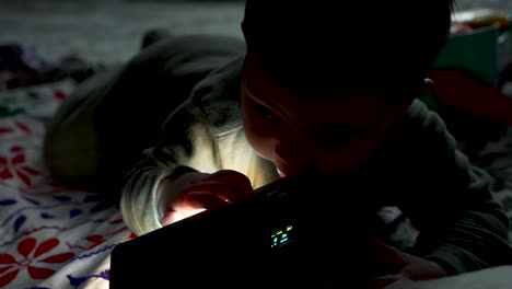 adorable 6 month old baby laying on floor interacting with led rbg light on floor in dark room