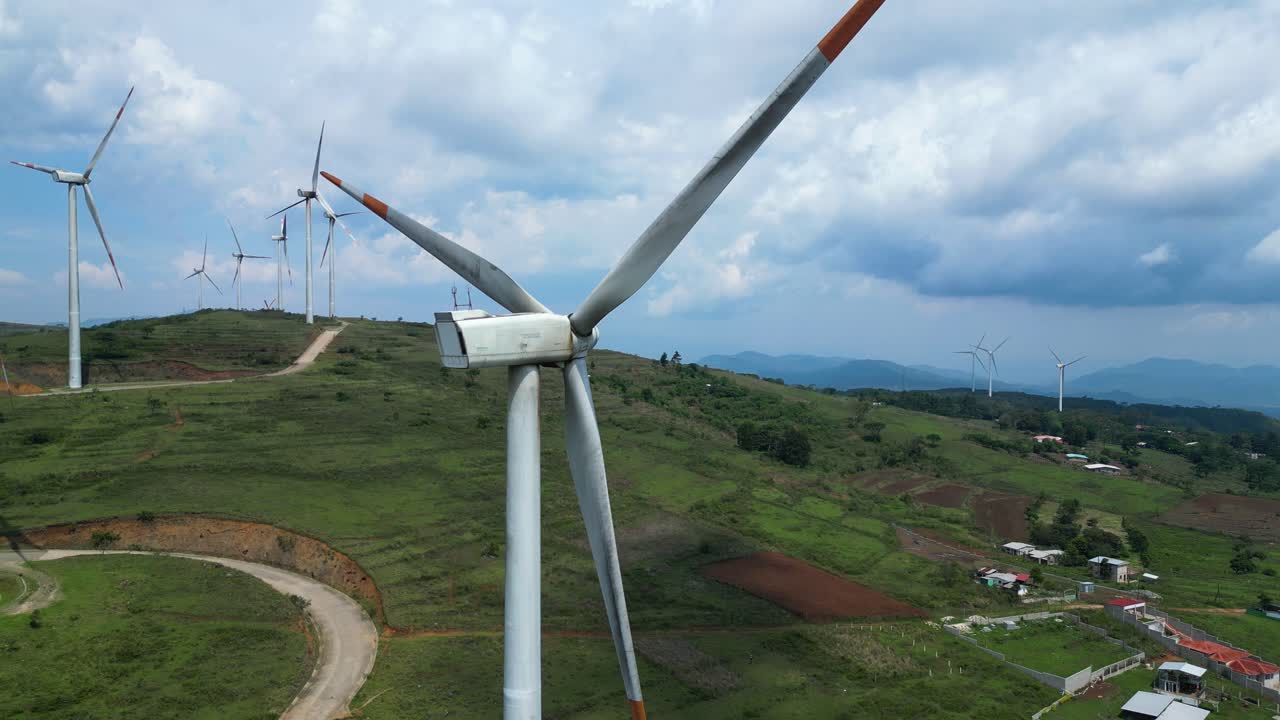 Close-up of wind turbine in rural hills with multiple turbines and farmlands