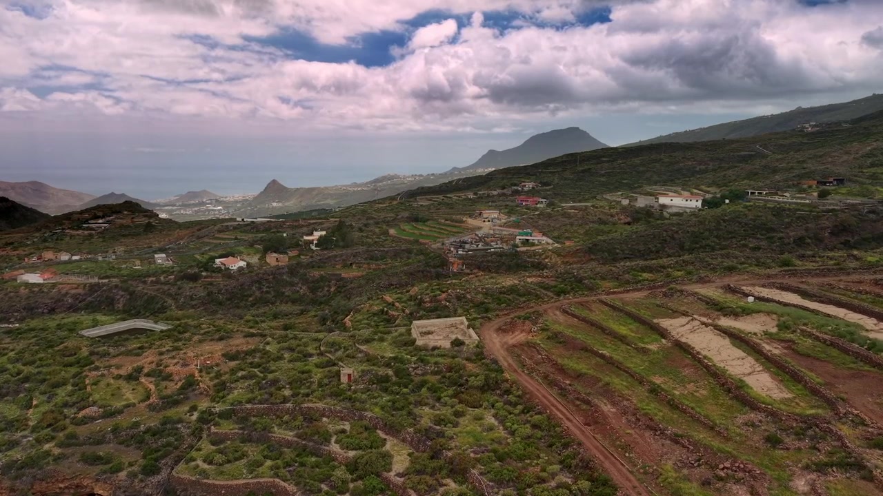 Vista aerea di colline vulcaniche terrazzate e case rurali sparse sotto cieli nuvolosi
