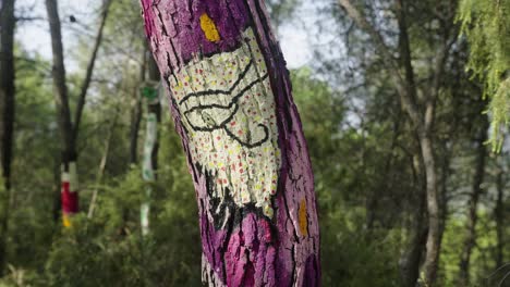 close up shot of colorful painted wooden tree in forest during sunny day in nature