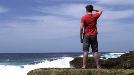 Hombre-De-Pie-En-La-Costa-De-La-Playa-De-Roca-Costera-Viendo-Las-Olas-Del-Océano-En-Contemplación,-Meditación