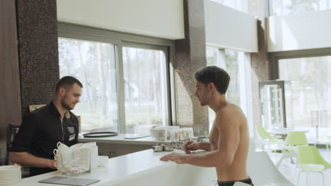 smiling man ordering bottle water in spa cafe