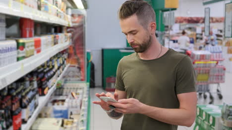 hombre comprando en una tienda de comestibles usando un teléfono inteligente