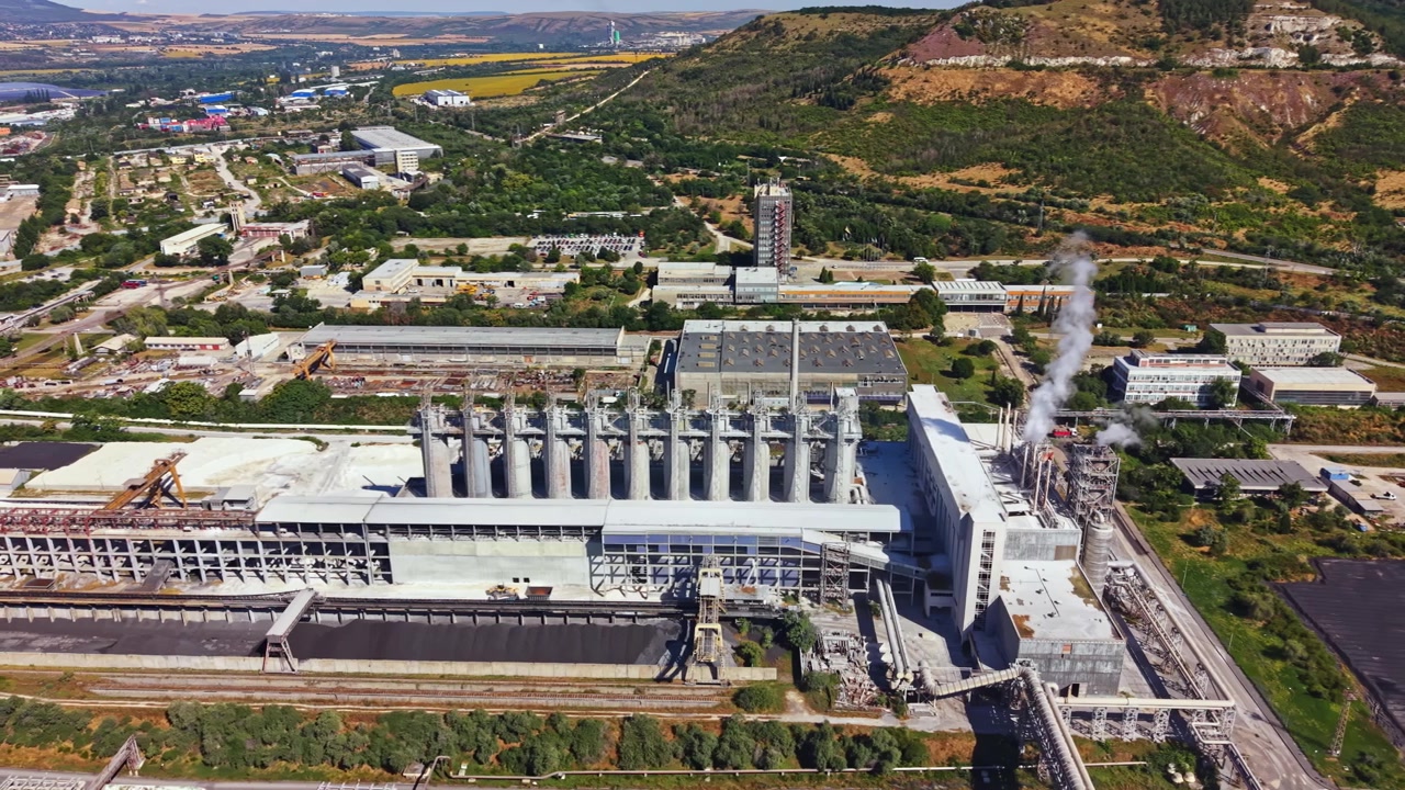 澄み切った空の下、山間部に位置する発電所が稼働している。工業用建物と緑豊かな風景が調和している。