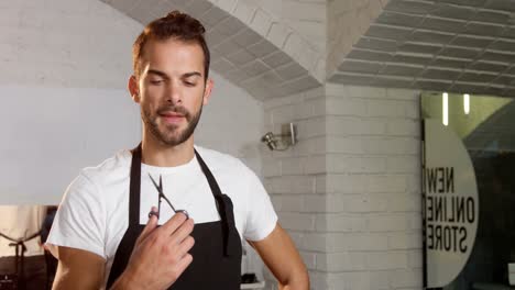 male hairdresser looking at scissor and smiling