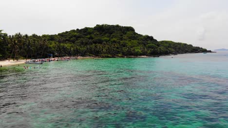 Flying-Low-over-Clear-Turquoise-Waters-and-Brightly-Colored-Coral-Reefs-next-to-Sandy-Beach-Shore-at-Gam-Ghi-island-in-Vietnam-Archipel-,-Phu-Quoc-Region