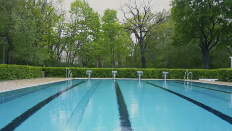 drone flying tight above the openair swimming pool heading towards the starting blocks