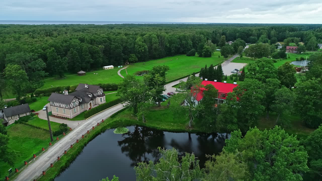 Bird's eye view of a mansion on a lake in a forest landscape