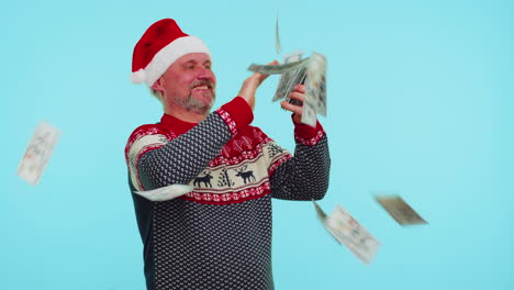 Rich-man-winner-in-Christmas-red-sweater-and-hat-showing-wasting,-throwing-money-around,-shopping