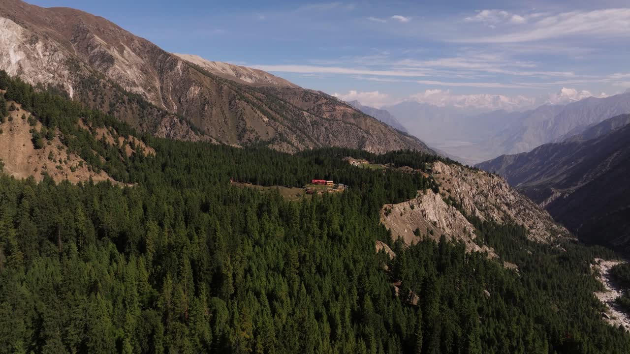 Aerial Establishing Shot Above Fairy Meadows Camp and Cabins, Dense Pine Forest and Rugged Mountain Cliffs
