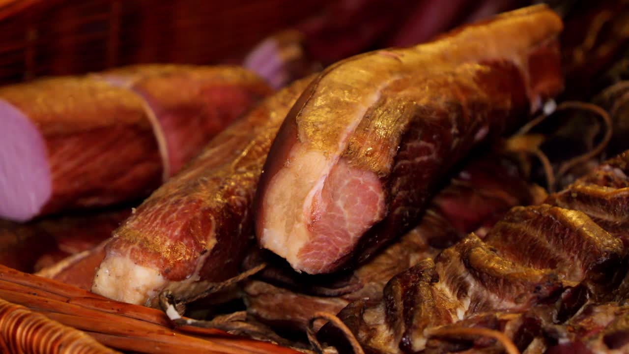 primer plano de tocino ahumado, jamón y carne fría dispuesta en cestas de mimbre