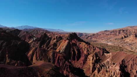 Afghanistan's-Red-City-In-Bamyan,-Man-Standing-On-Top-Of-Cliff-Overlooking-Scenery---aerial-drone-shot