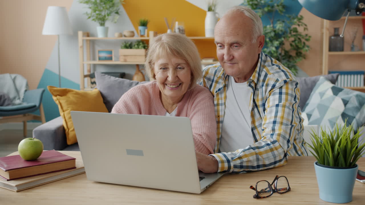 Una pareja de ancianos usando una computadora portátil en casa