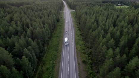 Atemberaubende-Drohnenaufnahme,-Die-Autos-Und-Lastwagen-Auf-Einer-Einsamen-Waldstraße-Im-Norden-Finnlands-Folgt