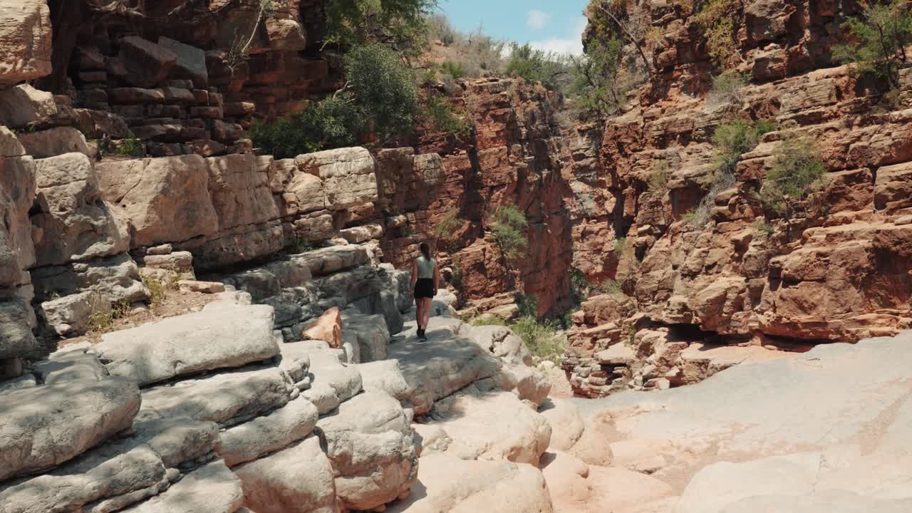 joven mujer caucásica caminando hasta el borde de un acantilado en el valle del paraíso, agadir, marruecos
