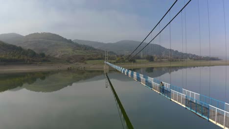 vuelo de avión no tripulado sobre el embalse de studen kladenets con una persona en el puente disfrutando de la vista de las montañas rodope de bulgaria