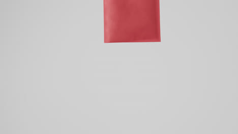 hand of caucasian woman holding red bag on white background, copy space, slow motion