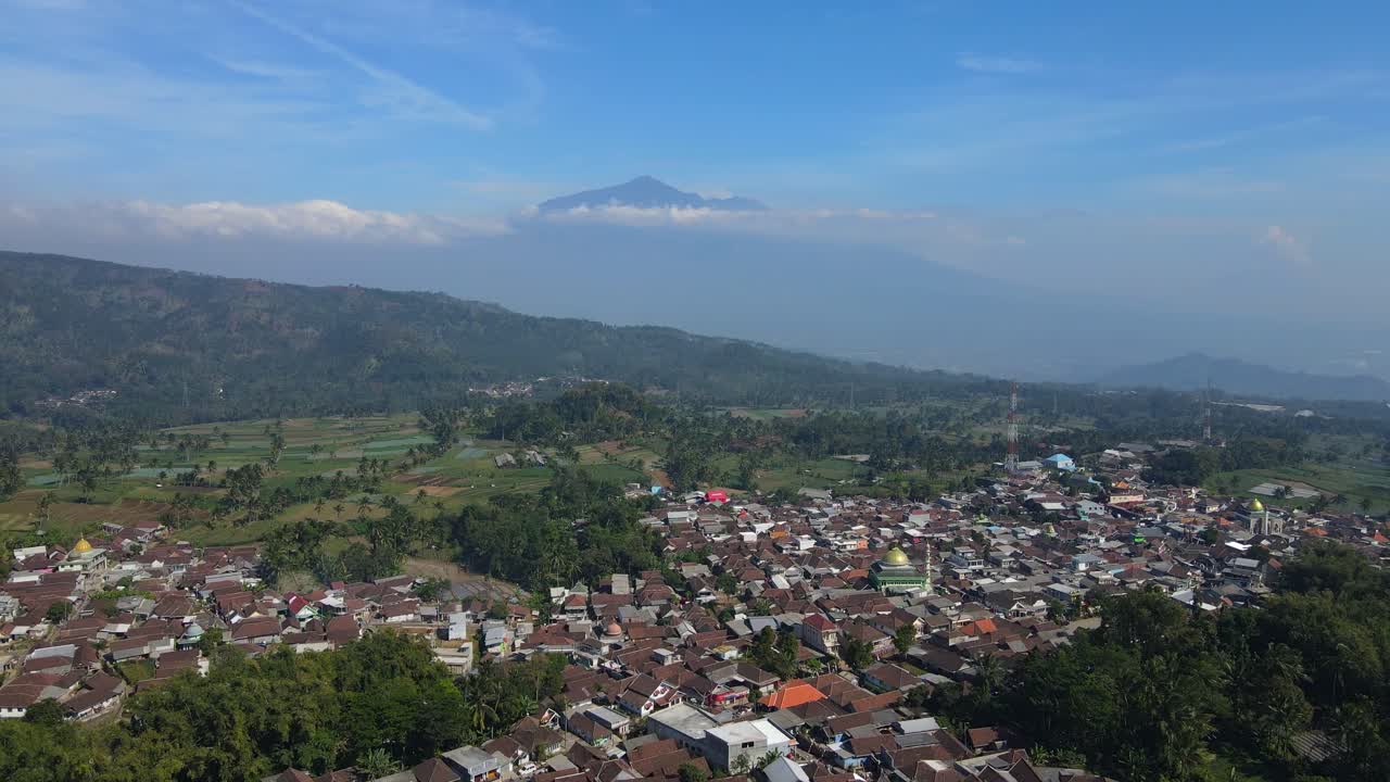4K aerial footage capturing a picturesque rural landscape with vast greenery and a breathtaking mountain view. Perfect for travel, nature, and documentary use