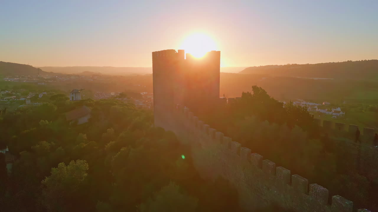 Silhouette castle tower sunset rising over old town drone view. Golden sunset