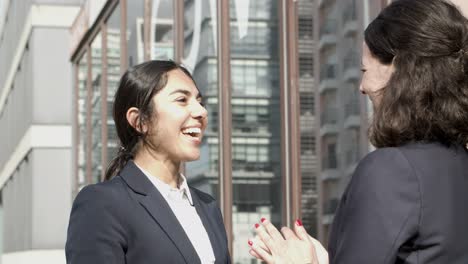 cheerful businesswomen hugging on street