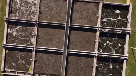 ascending top down view of aysa water purification plant in buenos aires, argentina containing square pools of dirty water before purification