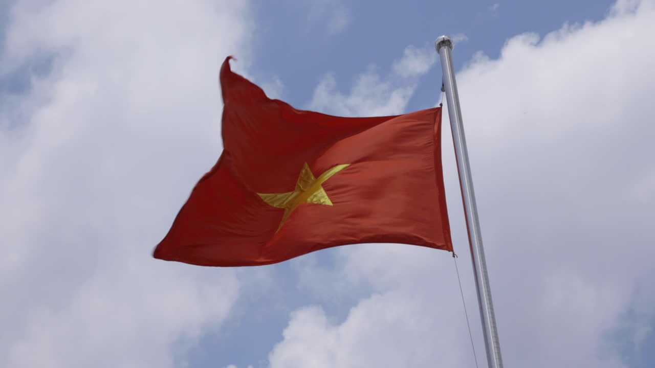 푸른 하늘과 구름 배경으로 밝은 태양 아래 베트남 국기의 4k 비디오