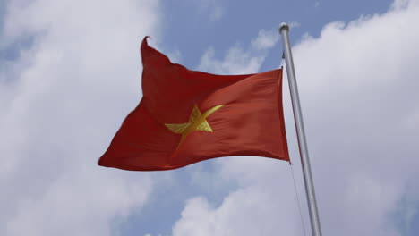 4k video of national flag of vietnam in bright sun with blue sky and cloud background