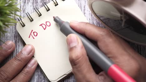 hand writing a to-do list on a notebook