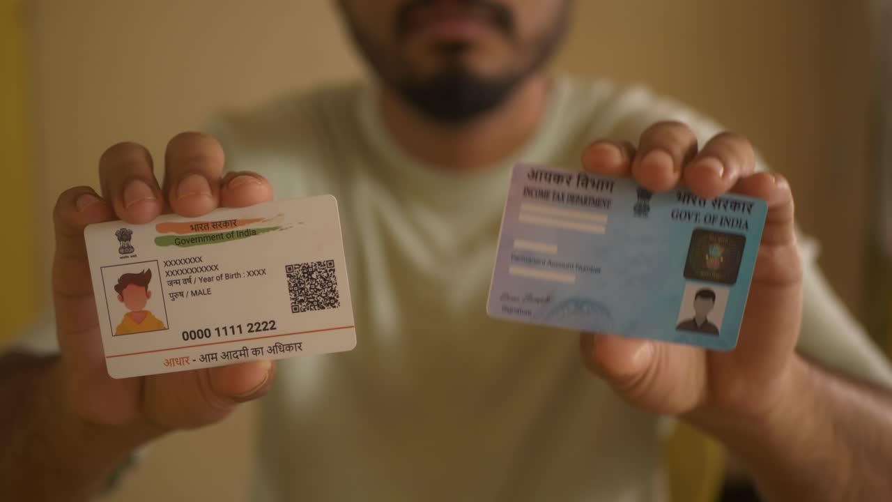 Indian nationality man holding PAN card from Income Tax Department and Aadhaar card, government programmes, closeup