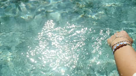 la mano de la mujer con las joyas tocando el agua cristalina. polinesia francesa día soleado